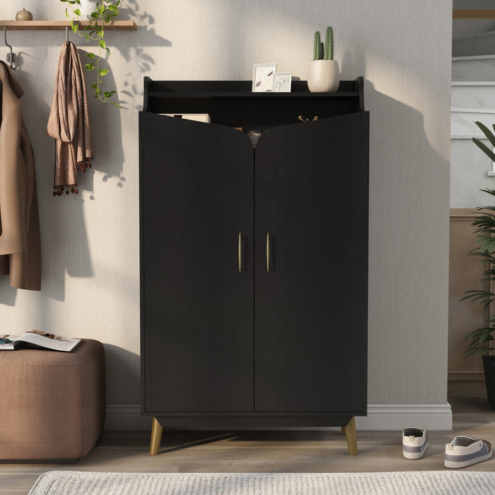 Front-facing modern black shoe cabinet with open upper shelf in foyer with accessories. Slim gold finish pulls and flared legs.