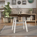 Slight right-angled rustic wood drop-leaf dining table with a wood finish top and white base in a casual breakfast nook with accessories