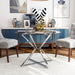 Left-angled modern glam dining table with a two-tone clear and chrome finish and bold, geometric base in a contemporary dining room with accessories