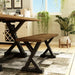 Left angled antique oak and black trestle bench in a living area with accessories