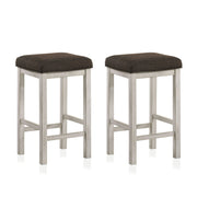 Right angled view of two rustic antique white counter height stools with dark brown fabric seats on a white background