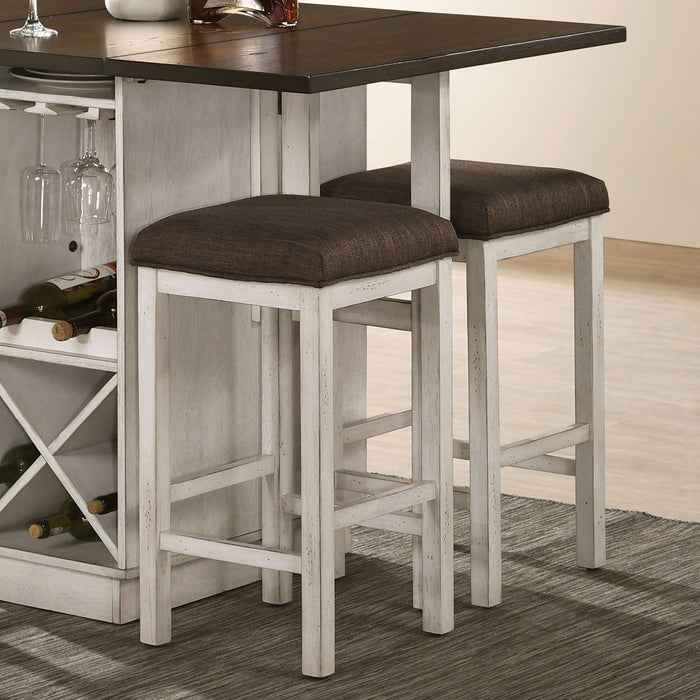 Right angled view of two rustic antique white counter height stools with dark brown fabric seats in a dining room beneath a matching counter table leaf extension