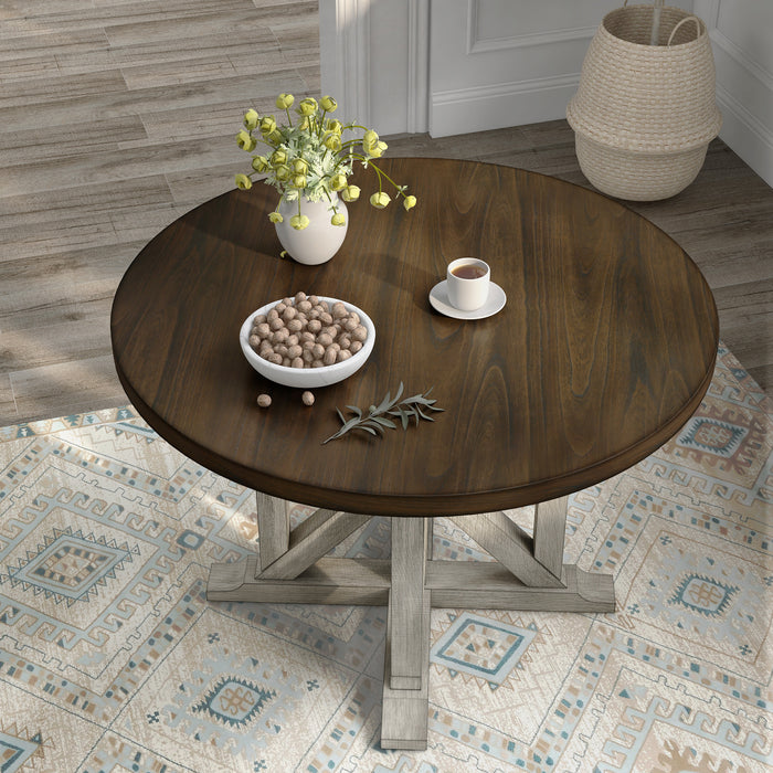 Top-down view of rustic dark oak round dining table with an antique white trestle pedestal base in a dining room with decor