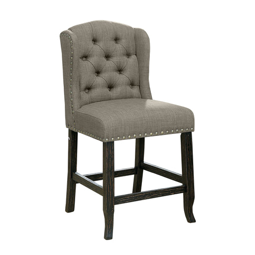 Right-angled grey counter-height chair against a white background. The button-tufted wingback chair and seat are accented in nailhead trim. An antique black leg frame offers footrests for comfort and rustic style.