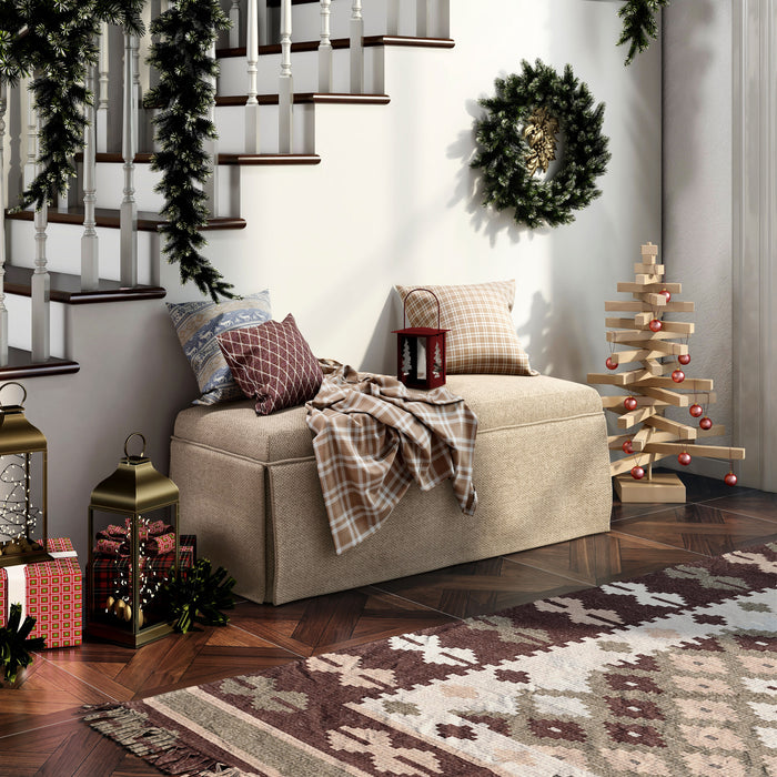 Beige upholstered and skirted farmhouse bench under staircase. Red and plaid throw pillows decorate the bench, while other Christmas decorations surround including a garland on the stair railing.