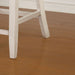 Left angled close up rustic counter height chair in antique white and gray leg detail in a dining room