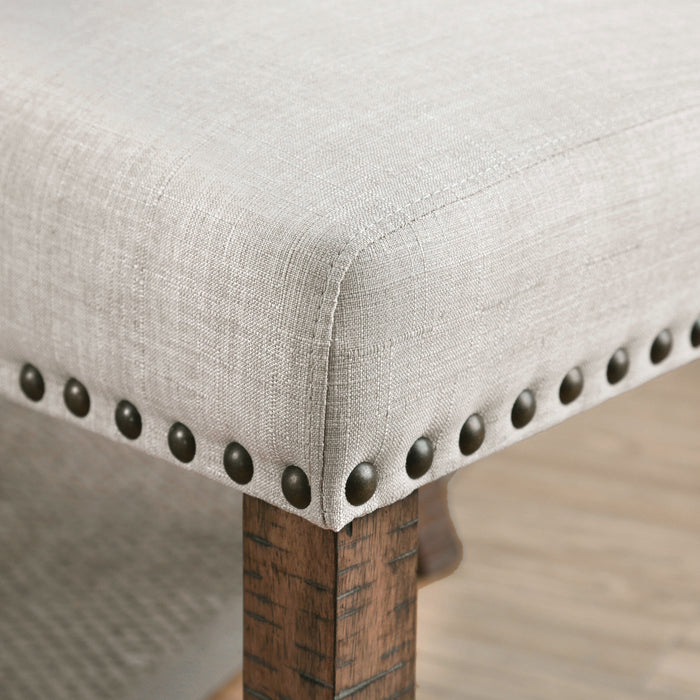 Left angled close up rustic pine and ivory button tufted dining chair upholstery and nailhead trim detail in a living area with accessories