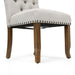Right angled close up rustic pine and ivory button tufted dining chair upholstery and leg detail on a white background