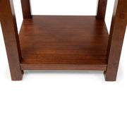 Front-facing top-down view of straight block legs and open bottom shelf of transitional cherry wood end table on a white background