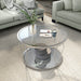 Modern round chrome coffee table with teardrop legs and mirrored lower shelves decorated in a living room.