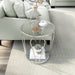 Modern round chrome side table with teardrop legs and mirrored lower shelves decorated in a living room.