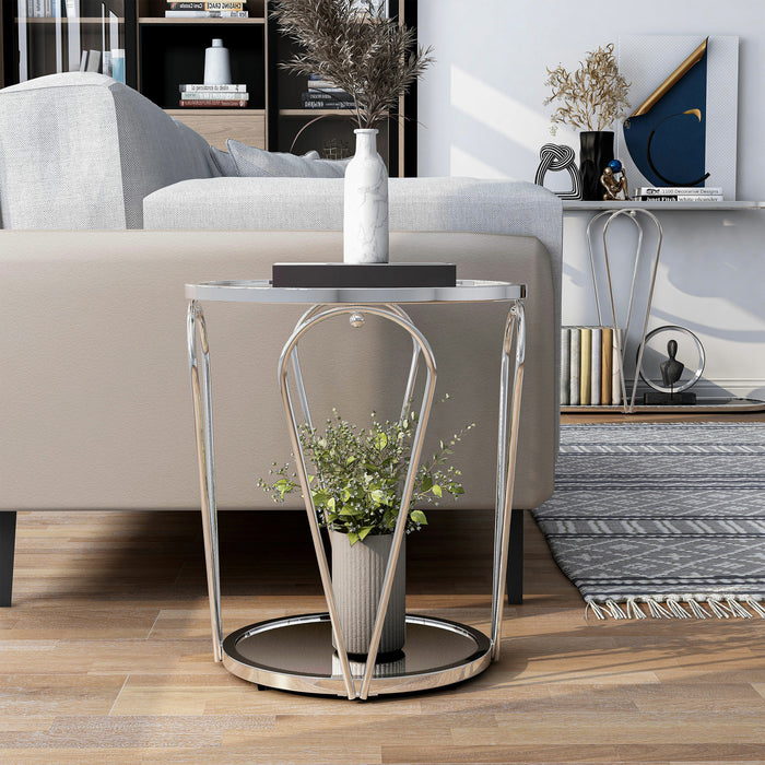 Front-facing modern round chrome end table with open teardrop shape steel legs, a clear tempered glass top, and mirror open bottom shelf decorated in a living room.