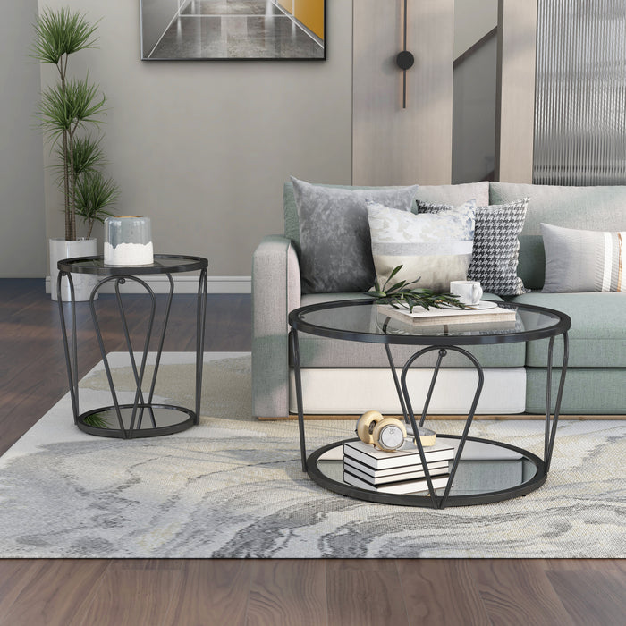 Front-facing view of modern round black nickel coffee table and end table with teardrop legs and mirrored lower shelf with decor next to living room sofa.