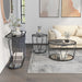 Front-facing side view of modern round black nickel coffee table, end table, and console table set with teardrop legs and mirrored lower shelves decorated in a living room