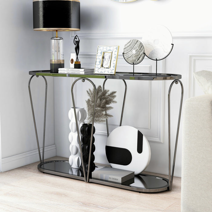 Left angled modern black nickel console table with open teardrop shape steel frame, a rounded gray tempered glass top, and mirror open bottom shelf decorated with art and lamp in living room corner.