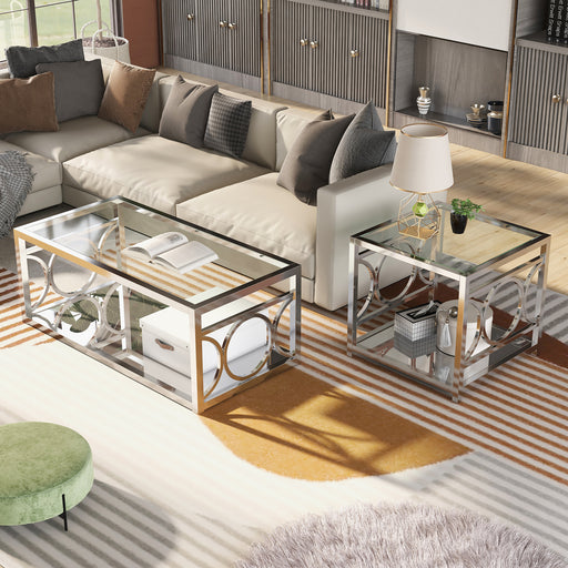 Left angled view of glam chrome steel coffee table and end table with ring motifs and mirrored bottom shelves decorated next to a living room sofa