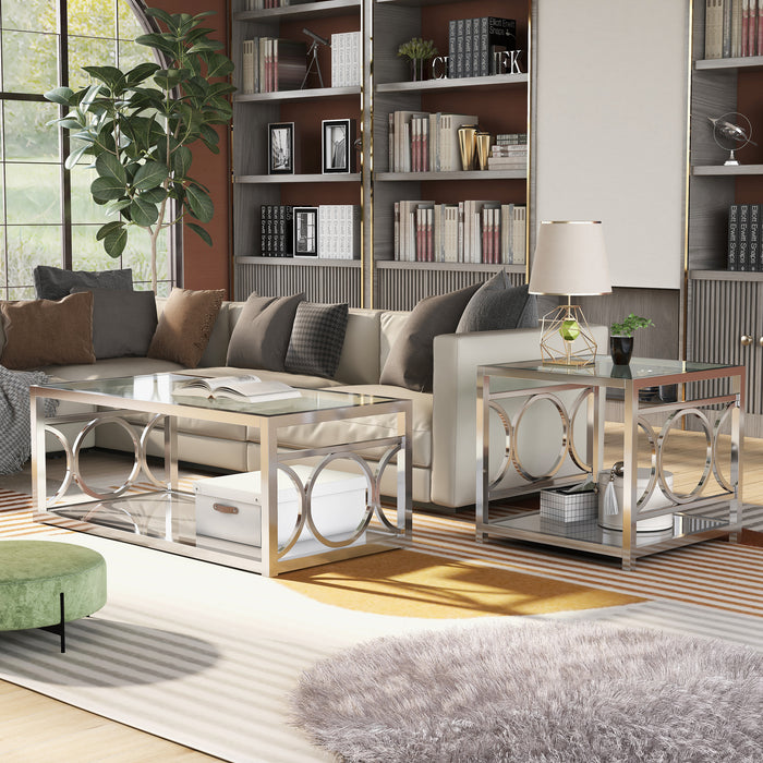 Left angled view of glam chrome steel coffee table and end table with ring motifs and mirrored bottom shelves decorated next to a living room sofa