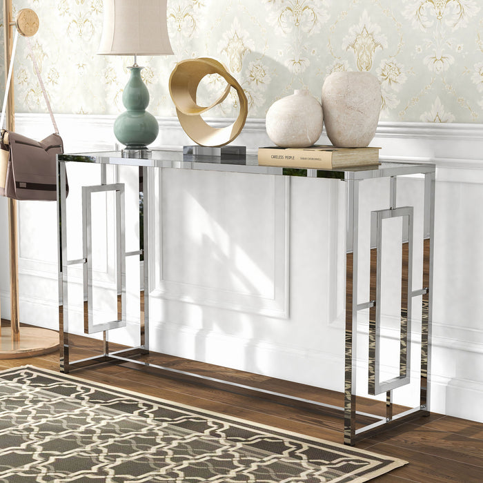 Left angled view of modern chrome plated steel sofa table with geometric trestle base and waterfall pattern tempered glass top decorated in a living room