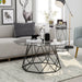 Semi-side facing contemporary black geometric coffee table with a octagon tempered glass top with furnishings and accessories.