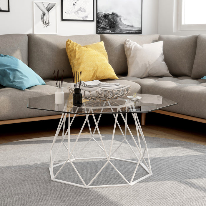 Elevated front-facing contemporary white geometric coffee table with a octagon tempered glass top on a white background with furnishings and accessories