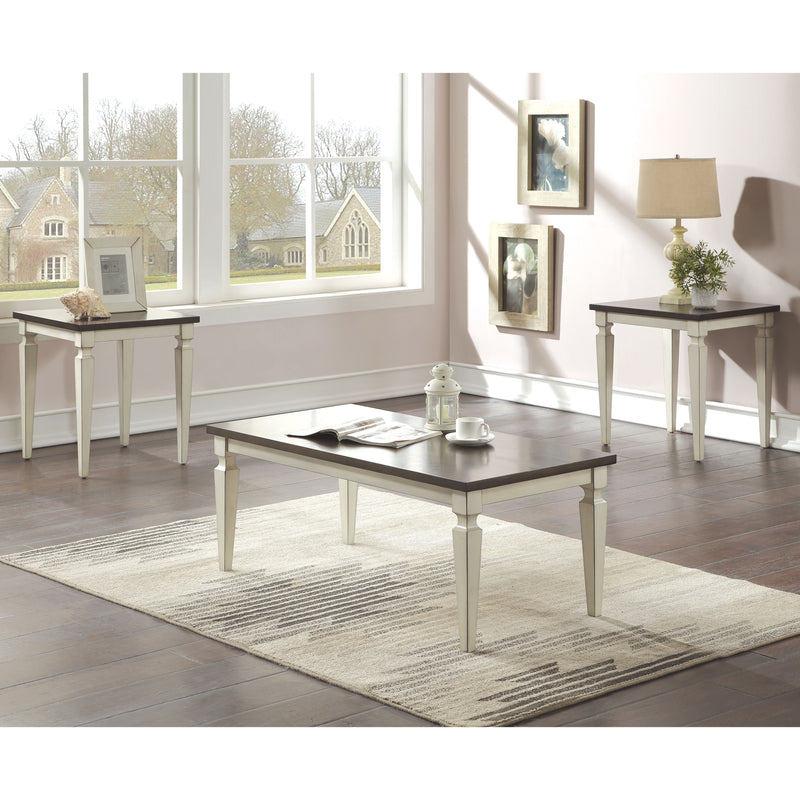 Semi-side facing view of transitional three-piece antique white and brown finish wood coffee table set in living room with accessories