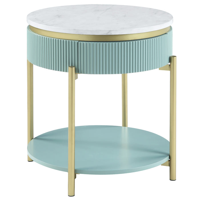 Right-facing glam light teal fluted end table with round faux white marble top and gold accents on white background. Single flush drawer and trestle legs with lower shelf.