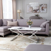 Left angled glam chrome and white geometric coffee table in a living room with accessories
