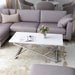 Left angled glam chrome and white geometric coffee table in a living room with accessories