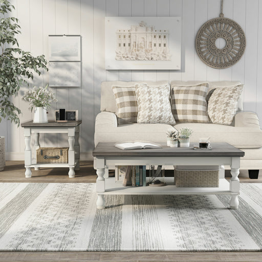Front-facing rustic gray wood coffee table and gray wood end table with antique white open shelf bases with decor in a transitional living room setting.
