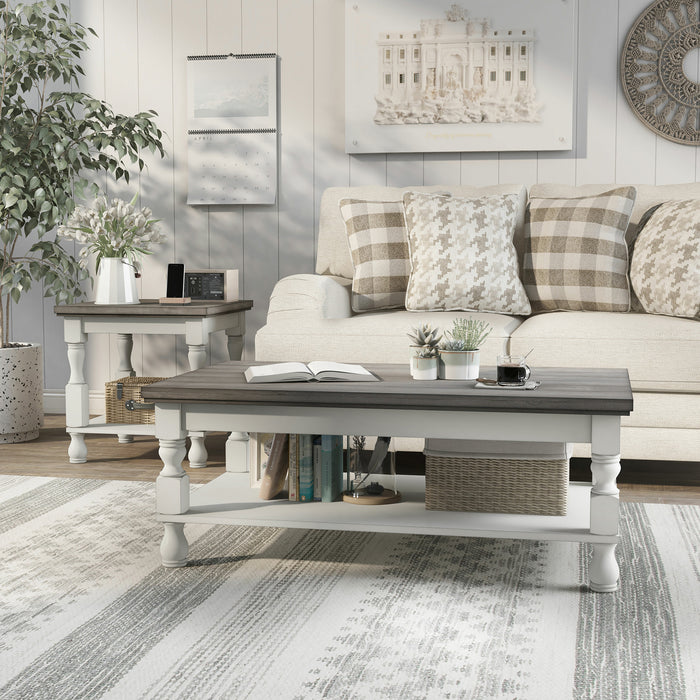 Left angled rustic gray wood coffee table and gray wood end table with antique white open shelf bases in a decorated transitional living room setting.