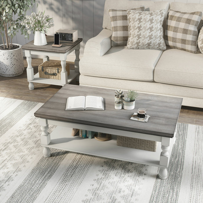 Left angled top-down rustic gray wood coffee table and gray wood end table with antique white open shelf bases in a decorated transitional living room setting.