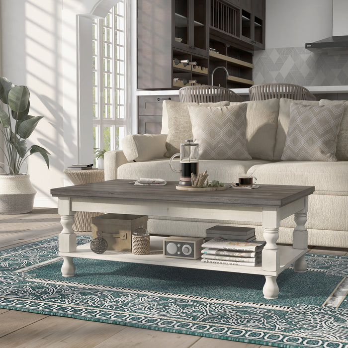 Left angled transitional one-shelf antique white and gray wood coffee table in a living room with accessories