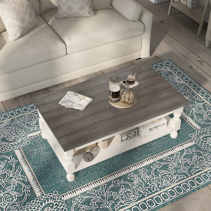 Right angled transitional one-shelf antique white and gray wood coffee table in a living room with accessories