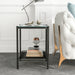 Front-facing modern industrial black steel end table with tempered white marble glass top, slender steel legs and perforated open metal shelf decorated next to a sofa.
