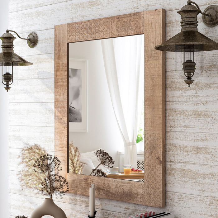 Angled side-facing view of natural finish mango wood framed rectangular decorative mirror in living space with accessories