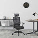 Right angled contemporary black adjustable office chair with headrest in an office with accessories