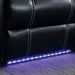 Right facing close up of LED lighting on a transitional black faux leather power recliner sofa with contrast stitching