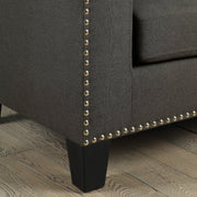Close-up view of railhead trim on lower corner of modern gray fabric sofa.