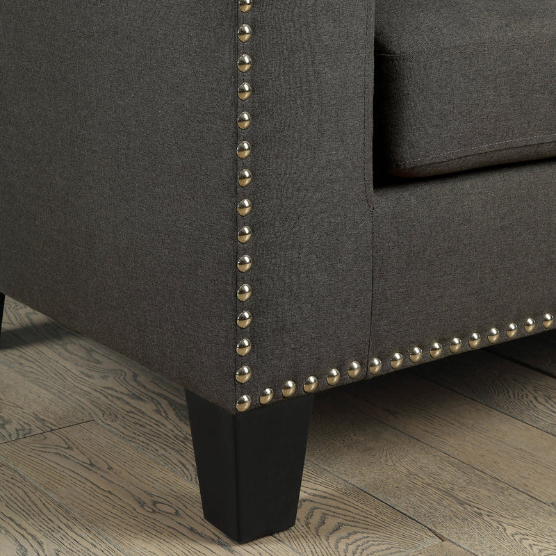 Close-up view of railhead trim on lower corner of modern gray fabric sofa.