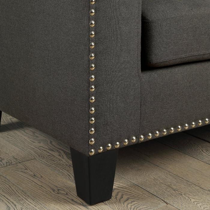 Close-up view of railhead trim on lower corner of modern gray fabric sofa.