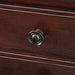Detail shot of a bronze bail knob on a traditional cherry nightstand. 