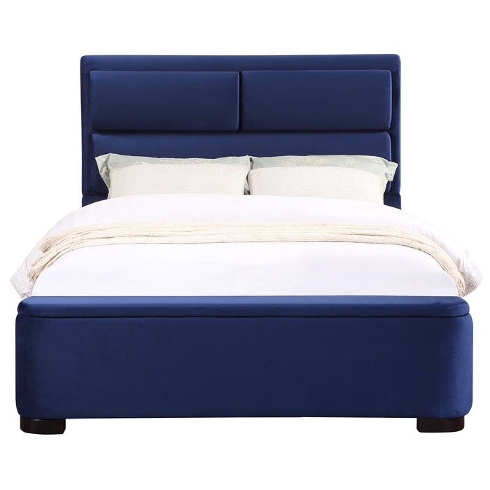 Front-facing modern glam navy blue upholstered bed with linens on a white background