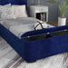Right-angled close-up of the storage footboard on a modern glam navy blue upholstered bed in a stylish bedroom with linens and accessories