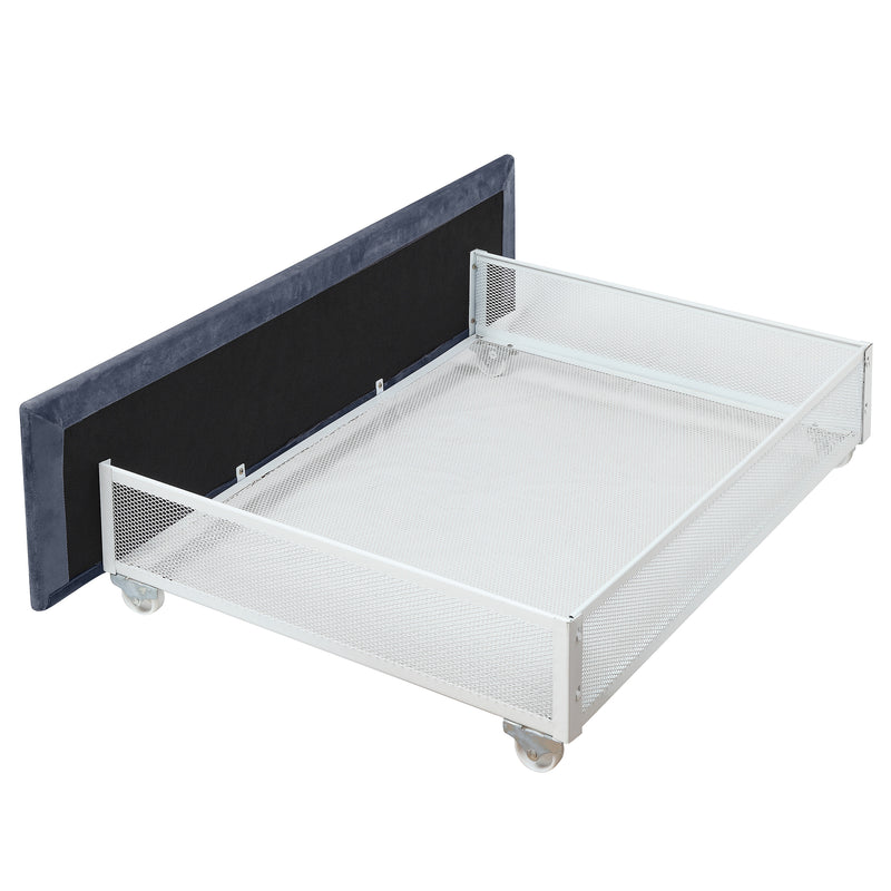 Left-angled side view close-up on the underbed drawer of a modern glam gray upholstered bed on a white background