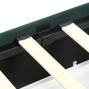 Left-angled close-up frame and underbed drawer detail view of a modern glam dark green upholstered storage bed with nailhead trim on a white background