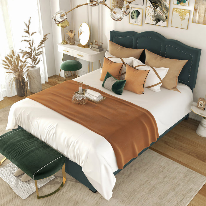 Left-angled top-down view of a modern glam dark green upholstered storage bed with panel-style nailhead trim and underbed drawers in a stylish bedroom with linens and accessories