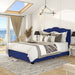 Left-angled modern glam navy blue upholstered storage bed with panel-style nailhead trim and underbed drawers in a stylish bedroom with linens and accessories