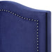 Right-angled close-up headboard detail of a modern glam navy blue upholstered storage bed with nailhead trim on a white background