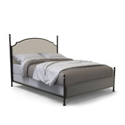 Right-angled California King-sized four-poster bed sits against a white background. The camelback is a beige upholstery while the frame of the bed is a gunmetal finish with slender posts that present ball finials.