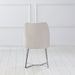Front-facing back view of a modern glam white microfiber dining chair with a geometric base in an empty room